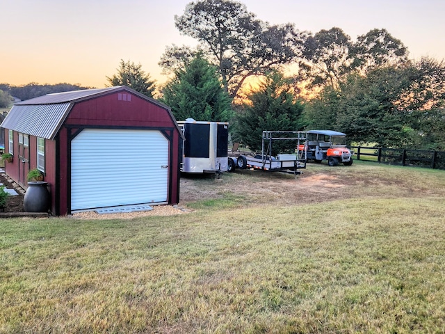 yard at dusk featuring a garage and an outdoor structure