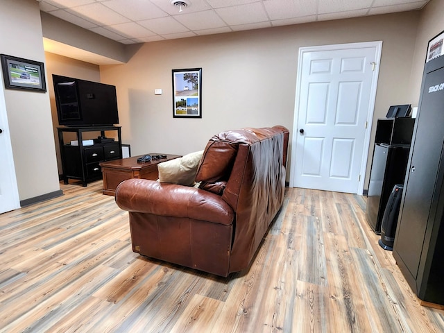 living room featuring a drop ceiling and light hardwood / wood-style floors