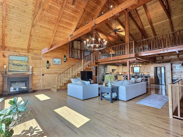 unfurnished living room with wood ceiling, high vaulted ceiling, beamed ceiling, hardwood / wood-style floors, and wood walls