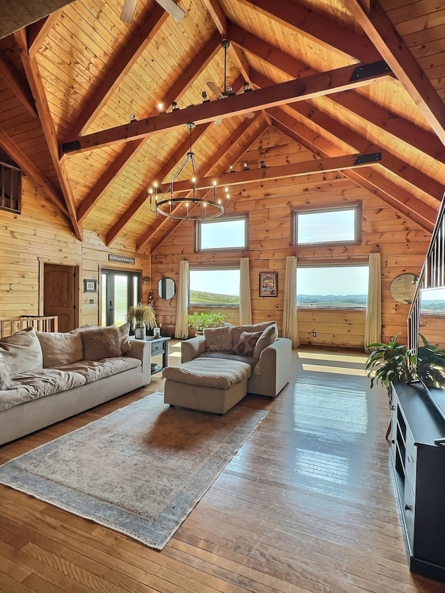 living room featuring wood ceiling, wooden walls, wood-type flooring, high vaulted ceiling, and an inviting chandelier