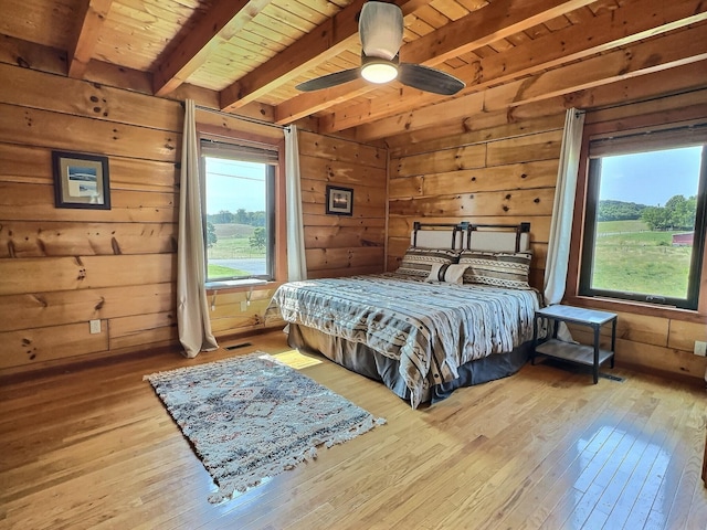 bedroom with wood ceiling, ceiling fan, beamed ceiling, light hardwood / wood-style floors, and wood walls