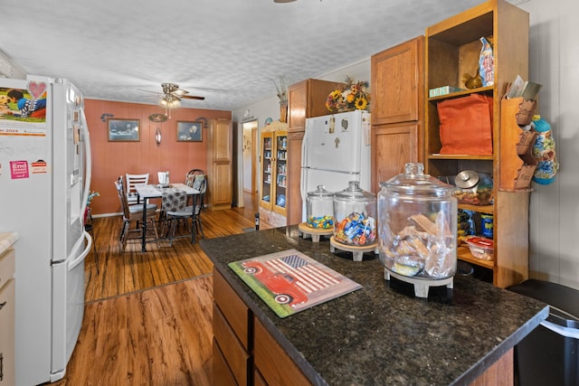 kitchen featuring ceiling fan, white fridge, wood-type flooring, and a textured ceiling