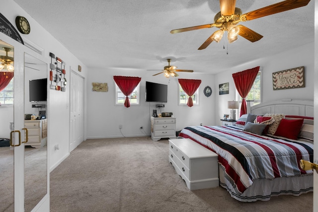 bedroom featuring ceiling fan, light colored carpet, a textured ceiling, and multiple windows