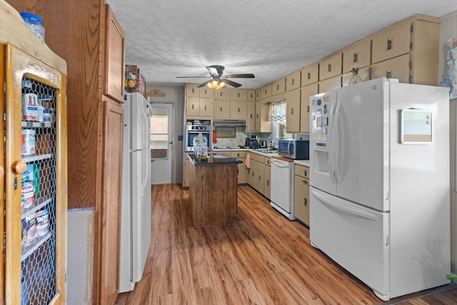 kitchen with white appliances, a textured ceiling, ceiling fan, a center island, and light hardwood / wood-style floors