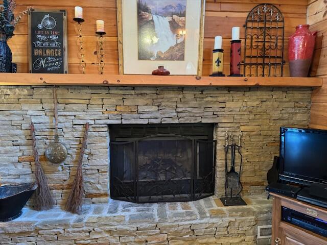 room details with a stone fireplace and wood walls