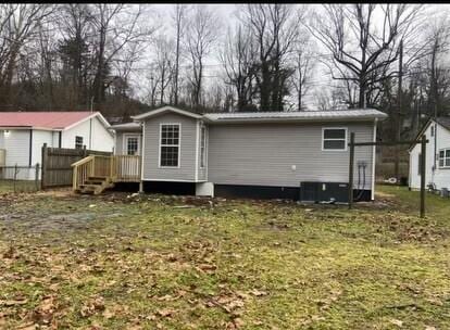 rear view of house with central AC and a lawn