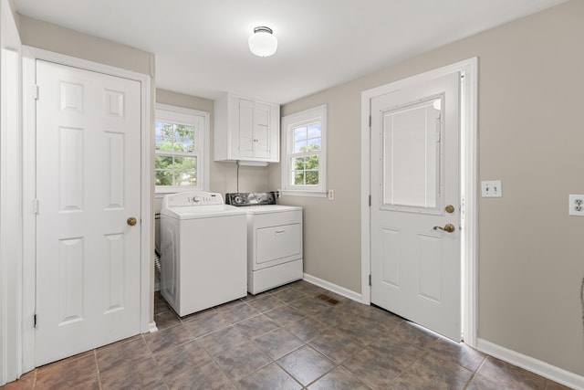 washroom with washer and dryer, a healthy amount of sunlight, and cabinets