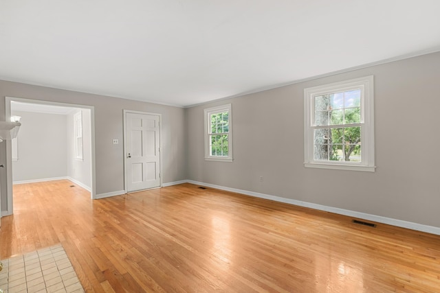 spare room with light hardwood / wood-style floors, crown molding, and a wealth of natural light