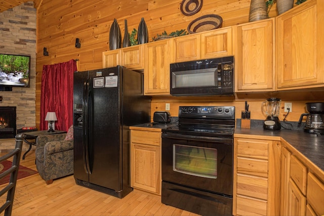 2040 Cougar Crossing Way, Sevierville, TN 37862 - kitchen with a stone fireplace, wood walls, light wood-style floors, black appliances, and dark countertops