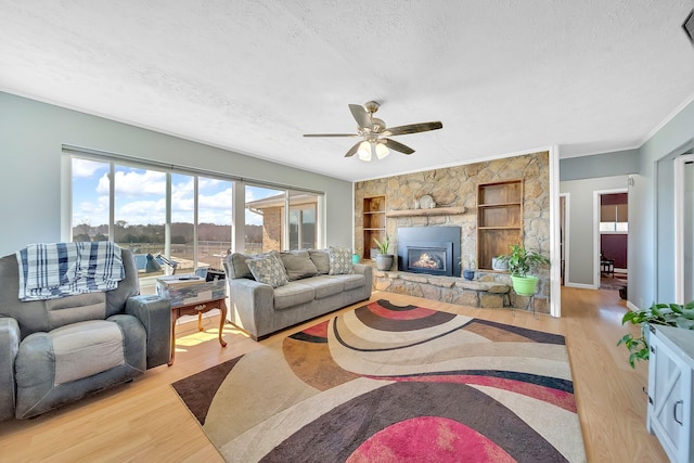1439 Woods Ridge Rd, Dandridge, TN 37725 - living area featuring wood finished floors, a textured ceiling, a ceiling fan, a stone fireplace, and crown molding