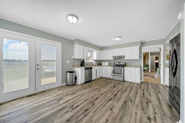 1439 Woods Ridge Rd, Dandridge, TN 37725 - kitchen featuring appliances with stainless steel finishes, light wood-style floors, light countertops, french doors, and a textured ceiling