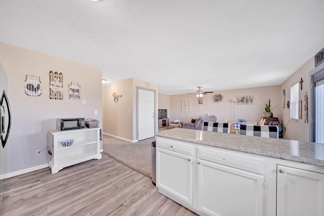1439 Woods Ridge Rd, Dandridge, TN 37725 - kitchen with open floor plan, white cabinetry, light wood-type flooring, a ceiling fan, and light stone counters