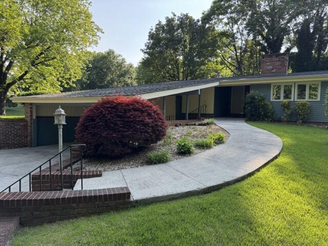 2414 Woodchuck Dell, Morristown, TN 37814 - view of front of house with concrete driveway, a front yard, a chimney, and a garage