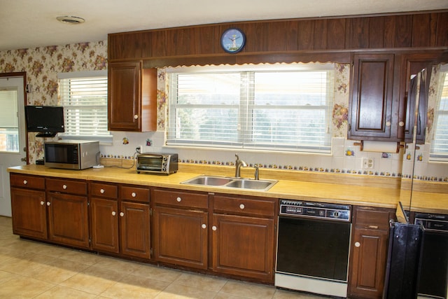 kitchen featuring black dishwasher, sink, decorative backsplash, and a wealth of natural light