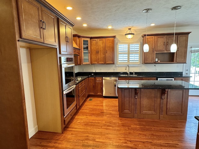 kitchen with appliances with stainless steel finishes, a wealth of natural light, pendant lighting, and dark stone countertops