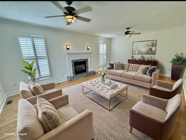 living room featuring ornamental molding, plenty of natural light, ceiling fan, and visible vents