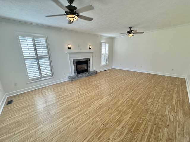 unfurnished living room featuring ceiling fan, light hardwood / wood-style floors, plenty of natural light, and a textured ceiling