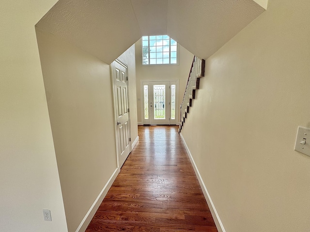 hall with vaulted ceiling, hardwood / wood-style floors, and a textured ceiling