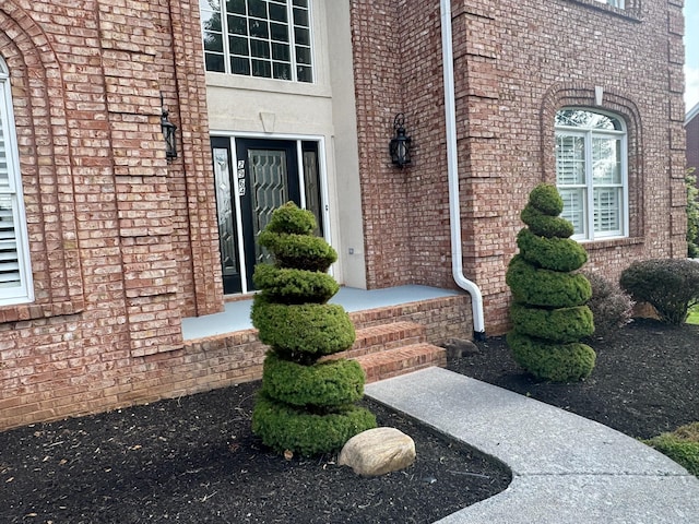 entrance to property featuring stucco siding and brick siding