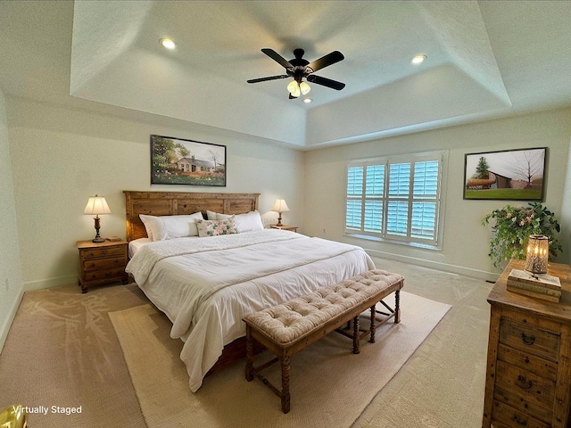 bedroom featuring baseboards, light carpet, and a tray ceiling