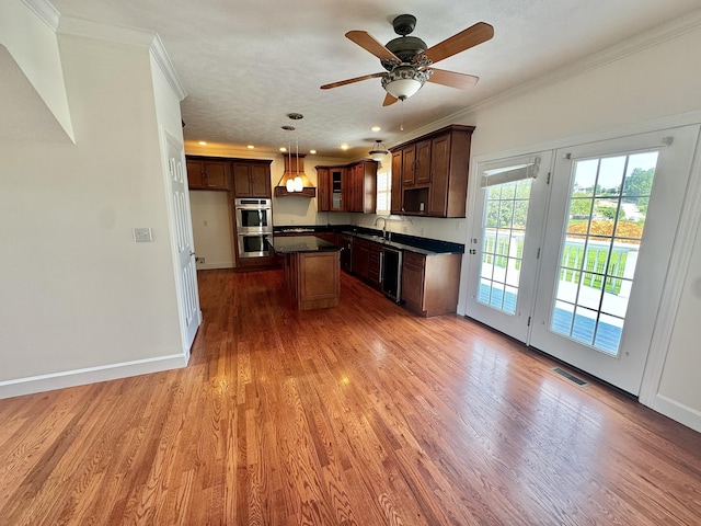 kitchen with stainless steel appliances, crown molding, sink, a kitchen island, and hanging light fixtures