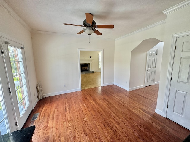 empty room with a textured ceiling, ceiling fan, crown molding, hardwood / wood-style floors, and radiator heating unit