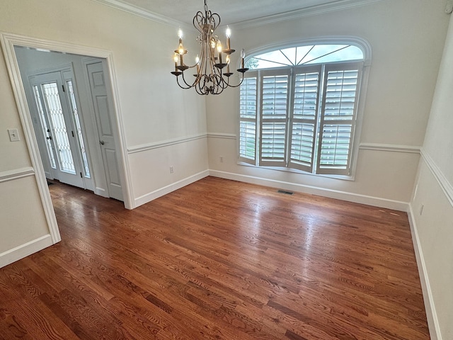 unfurnished dining area with wood finished floors, ornamental molding, baseboards, visible vents, and a notable chandelier