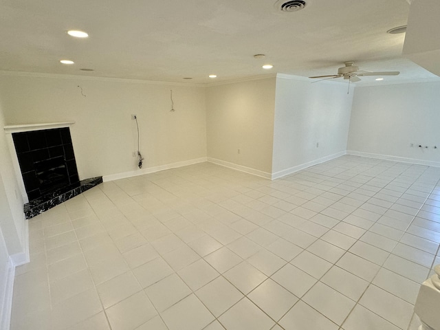 spare room featuring a tile fireplace, light tile patterned floors, ceiling fan, and crown molding