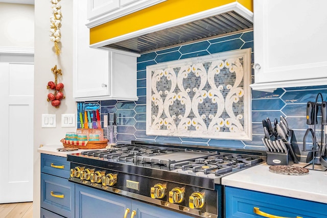 kitchen with blue cabinetry, premium range hood, backsplash, stainless steel gas stovetop, and white cabinets