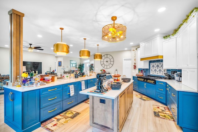 kitchen with blue cabinetry, white cabinetry, ceiling fan, hanging light fixtures, and stainless steel gas cooktop