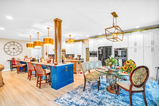 kitchen with white cabinets, decorative light fixtures, and an island with sink