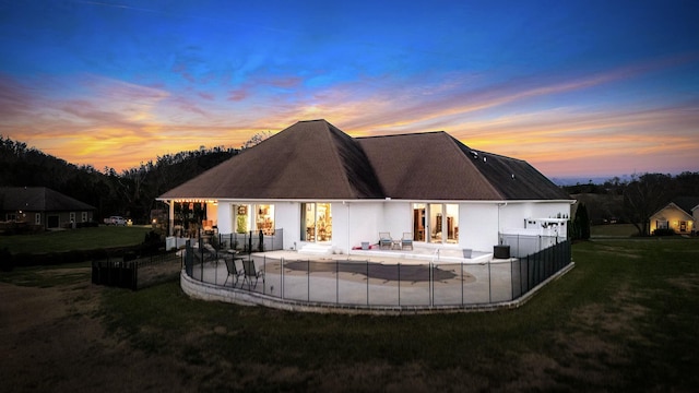 back house at dusk featuring a yard