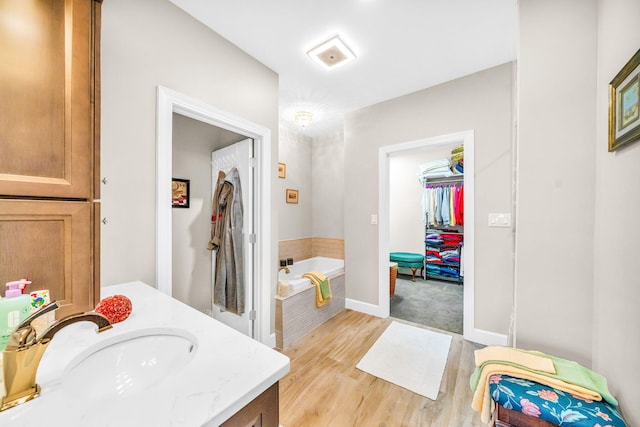 bathroom with tiled tub, vanity, and hardwood / wood-style flooring