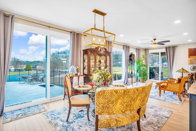 dining room featuring ceiling fan with notable chandelier and light hardwood / wood-style flooring
