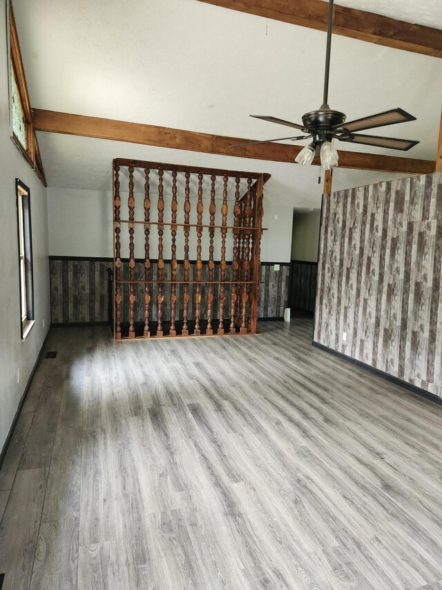 unfurnished living room with hardwood / wood-style floors, lofted ceiling with beams, and ceiling fan