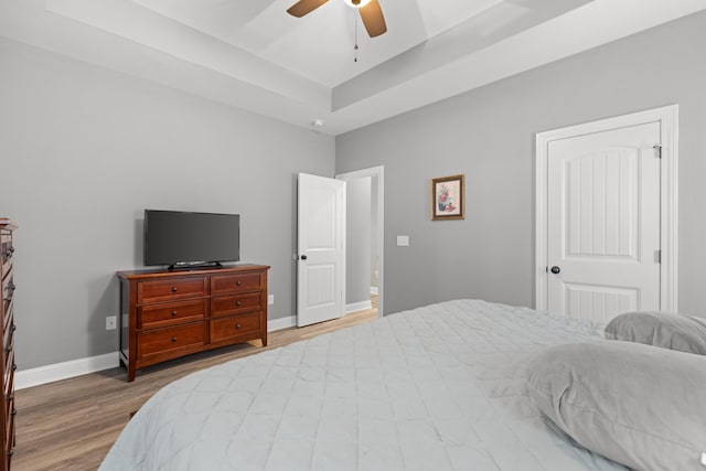 bedroom featuring ceiling fan, a raised ceiling, and hardwood / wood-style flooring