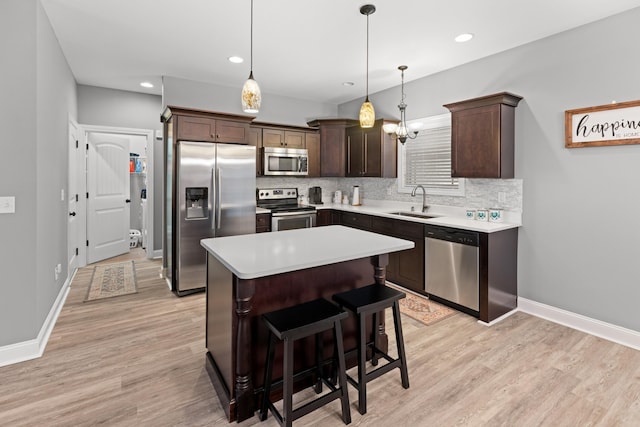 kitchen featuring stainless steel appliances, sink, a center island, hanging light fixtures, and a breakfast bar