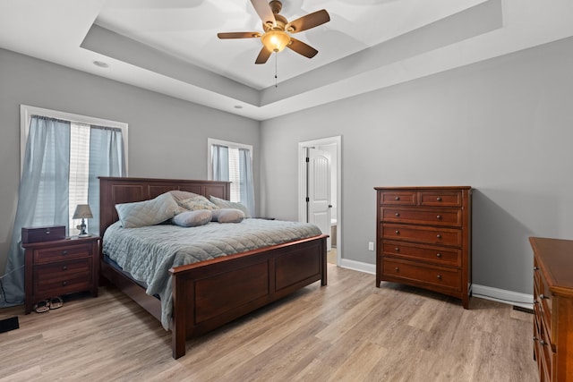 bedroom featuring a raised ceiling, ceiling fan, and light hardwood / wood-style floors