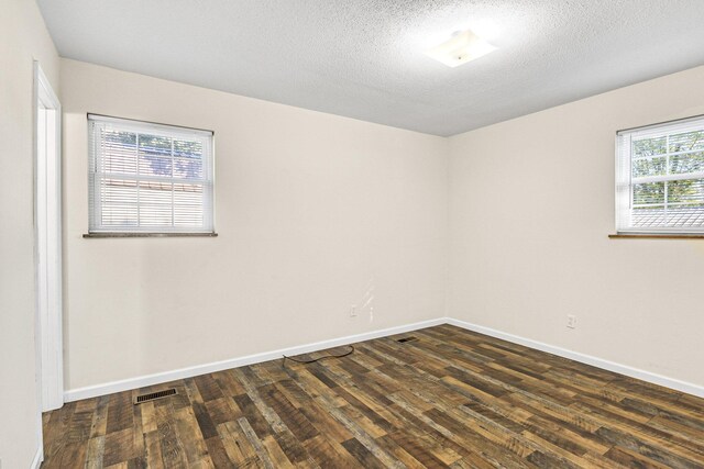 empty room with a textured ceiling and dark wood-type flooring