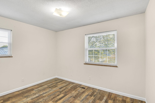 unfurnished room with a textured ceiling, dark wood-type flooring, and a wealth of natural light