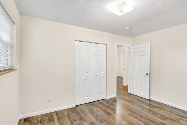 unfurnished bedroom with dark hardwood / wood-style flooring, a textured ceiling, and a closet