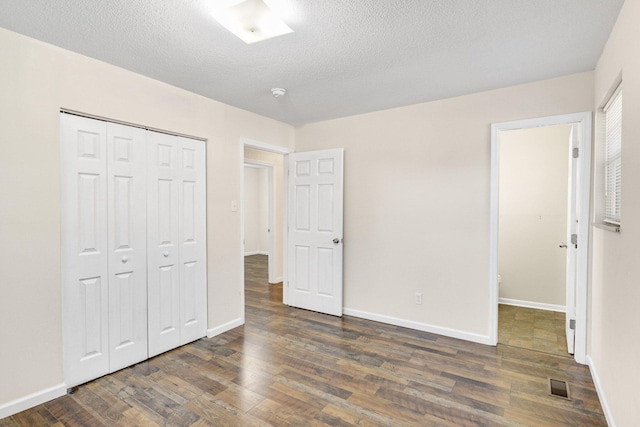 unfurnished bedroom featuring a textured ceiling, a closet, and dark hardwood / wood-style floors