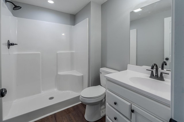 bathroom featuring a shower, vanity, hardwood / wood-style flooring, and toilet