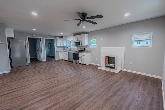 unfurnished living room featuring dark hardwood / wood-style flooring, ceiling fan, and sink