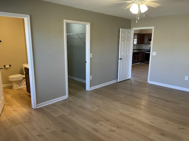 unfurnished bedroom with a spacious closet, ensuite bath, light hardwood / wood-style floors, and a closet