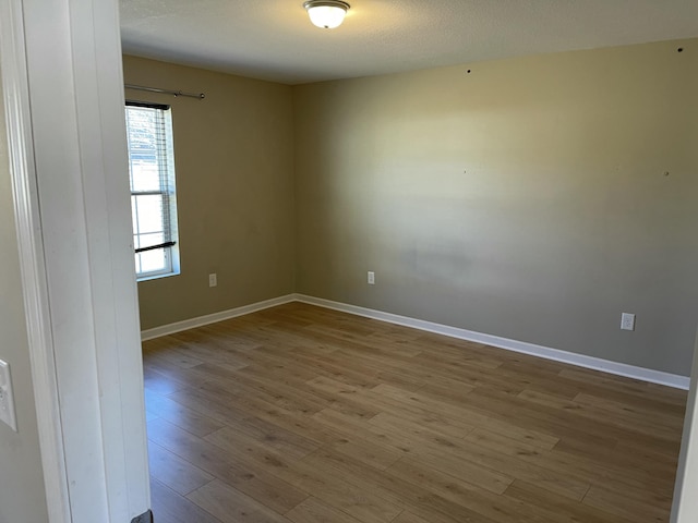 spare room featuring light hardwood / wood-style flooring and a textured ceiling