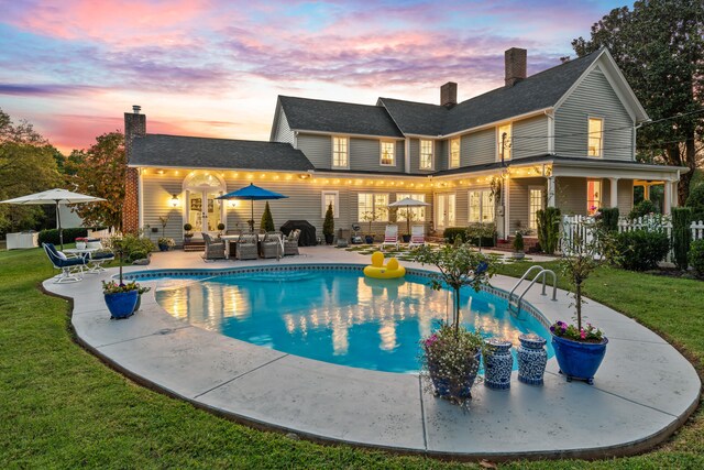 back house at dusk featuring a patio area, an outdoor hangout area, a fenced in pool, and a yard