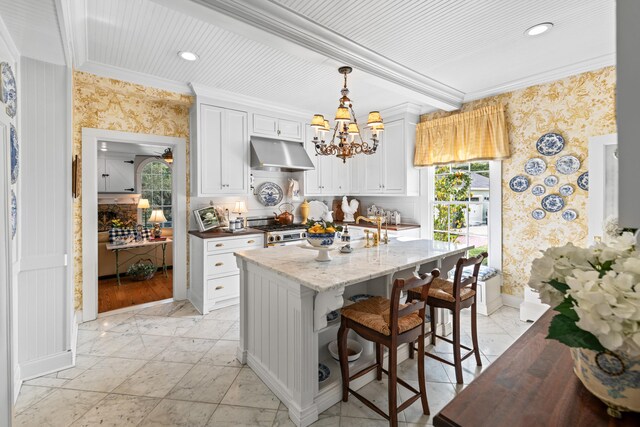 kitchen featuring pendant lighting, high end stainless steel range oven, ornamental molding, light stone counters, and white cabinetry