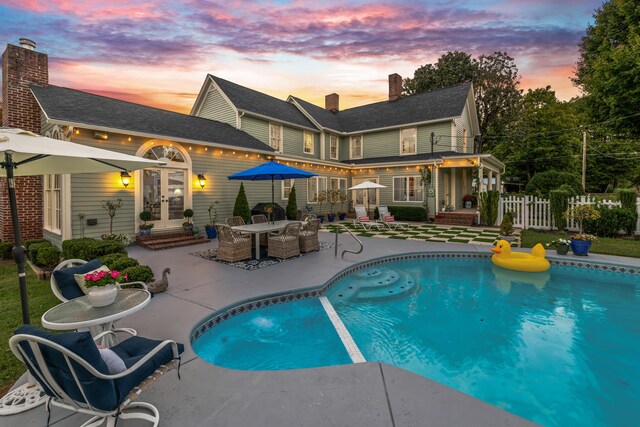 pool at dusk with a patio area