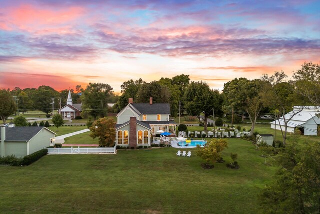 back house at dusk with a lawn